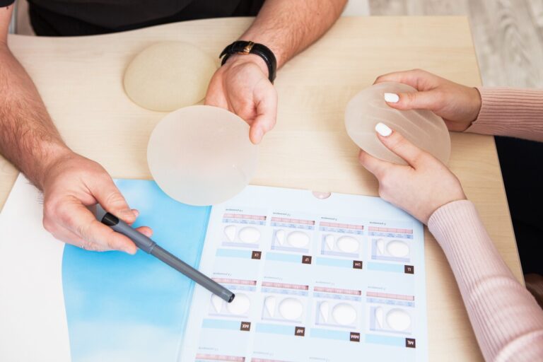 A plastic surgeon doctor shows a sample set of a silicone implants for breast reduction to a female patient in the clinic