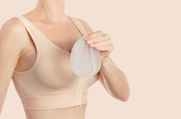 woman in compression bra holding an implant