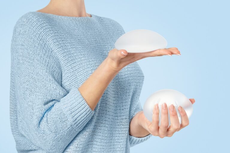 woman holding the breast implants removed from her