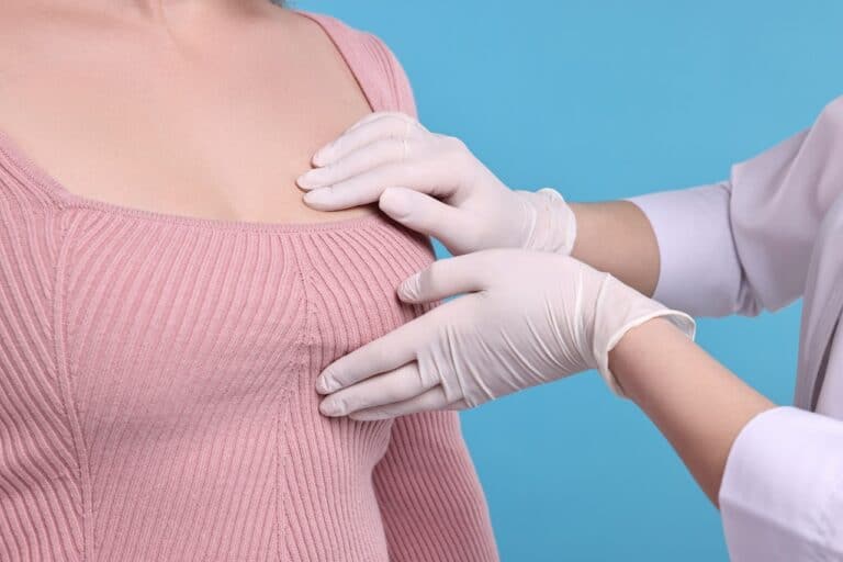 doctor in latex gloves checking woman's chest